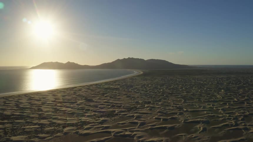Coastal beach with a bright sun in a clear blue sky