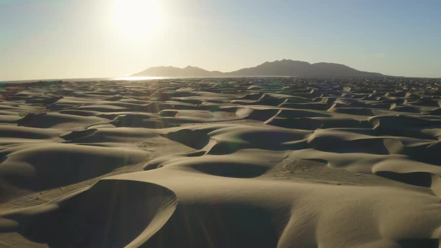 Desert with mountains on the horizon and a bright sun in the sky