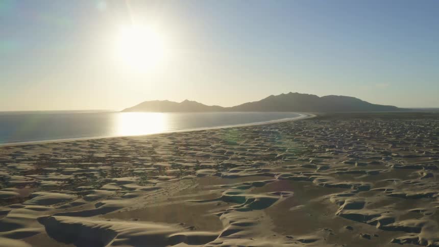 Coastal beach with a bright sun in a clear blue sky