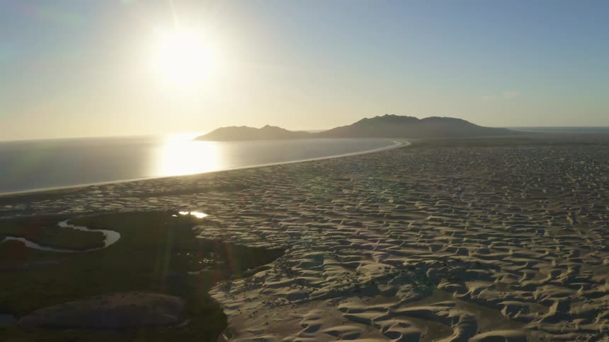 Coastal beach with a bright sun in a clear blue sky