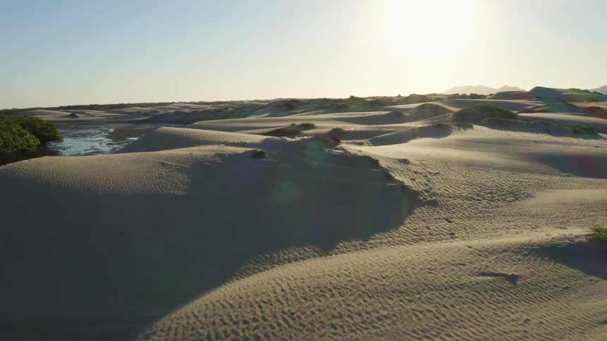 The stream runs by the hills of sand