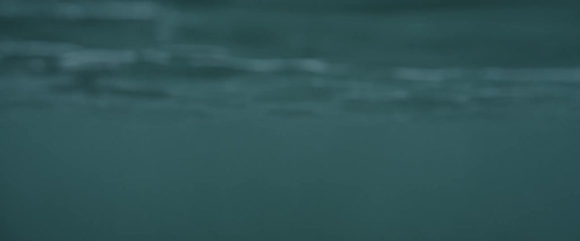 Woman wearing a black wet suit sitting on a surfboard in the ocean