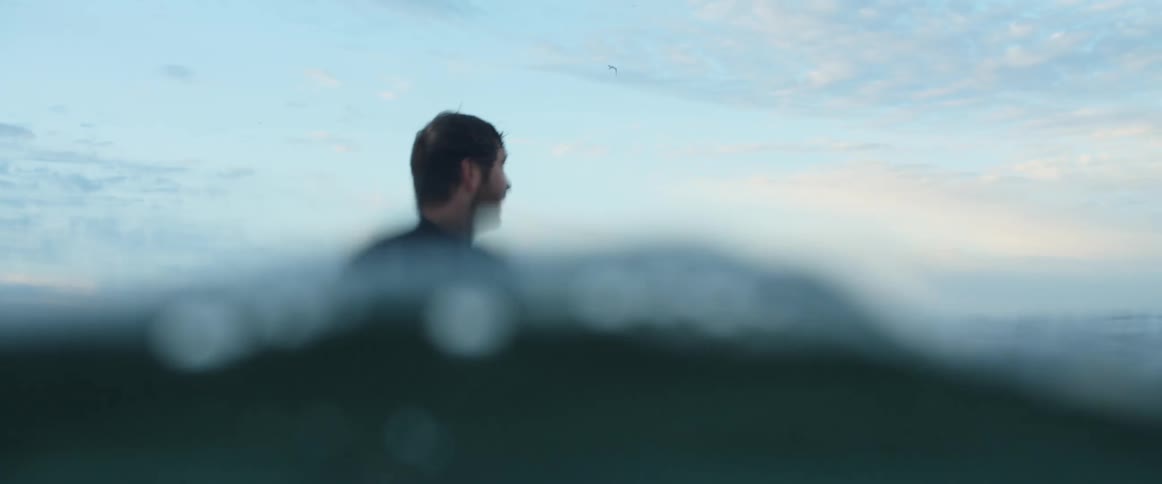 A man is standing in the water on a cloudy day
