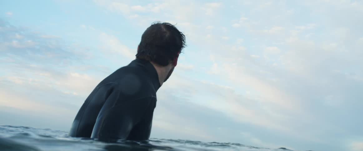 A man swimming in the ocean looking around during the day