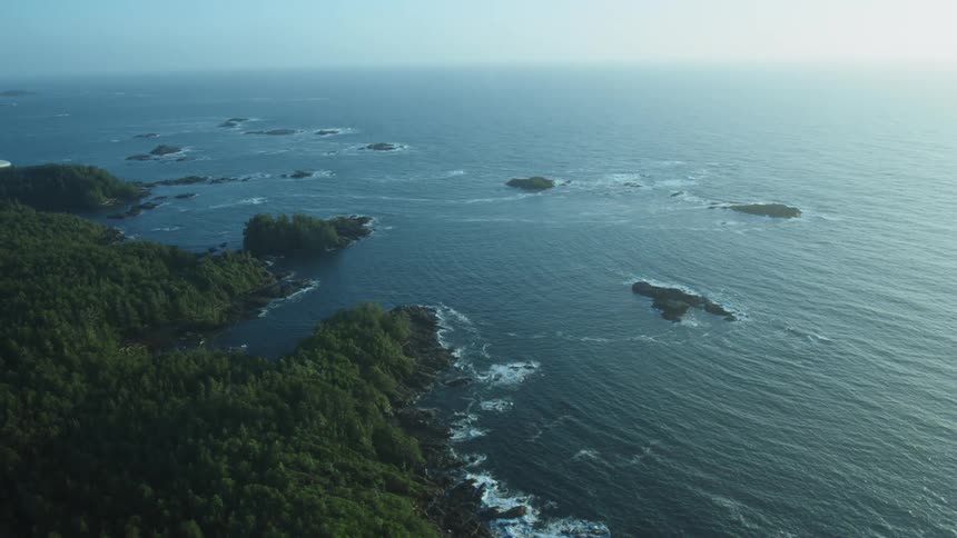 A coast with water and waves with islands with trees with the sky and clouds in the background
