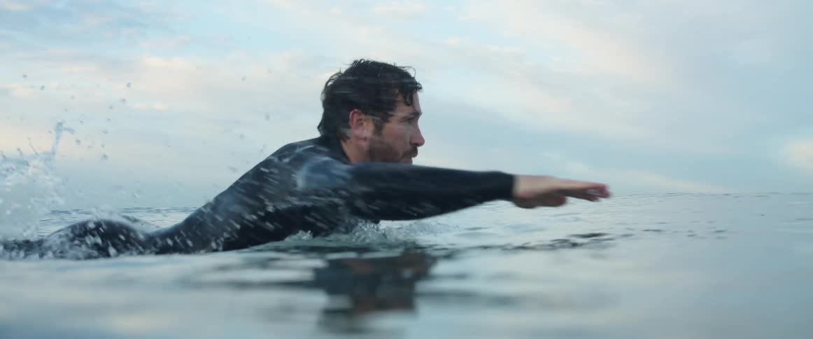 A man is traveling in the water on his surfboard