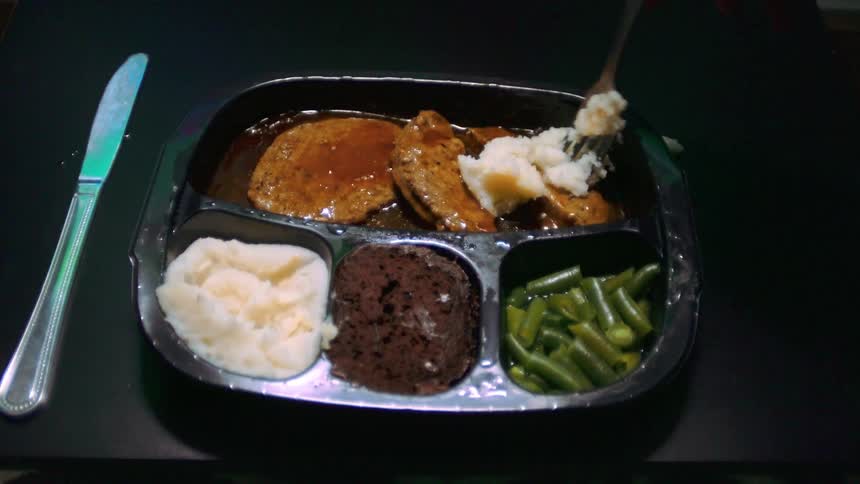 A person uses a fork to mix mashed potatoes with some beef before picking it up to eat