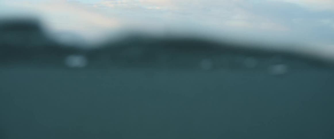 A man stands in the ocean as waves roll