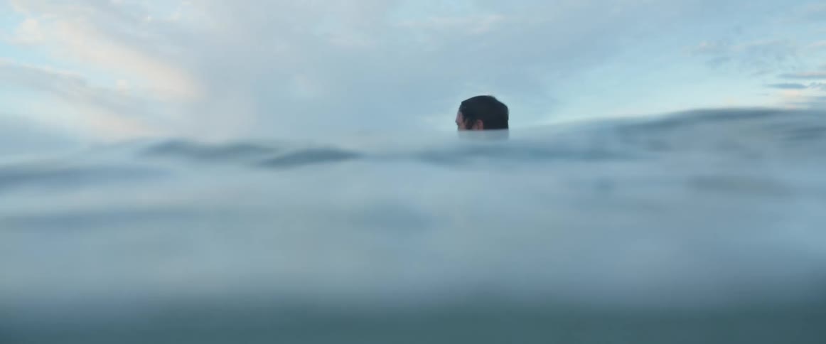 A surfer in a wet suit floating in ocean water