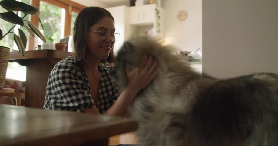 A woman petting her dog in her house