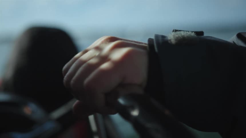 A man on the steering wheel of a boat navigating on a lake