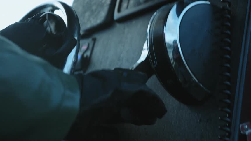 A person wearing dark gloves spins the steering wheel of a boat while adjusting the throttle