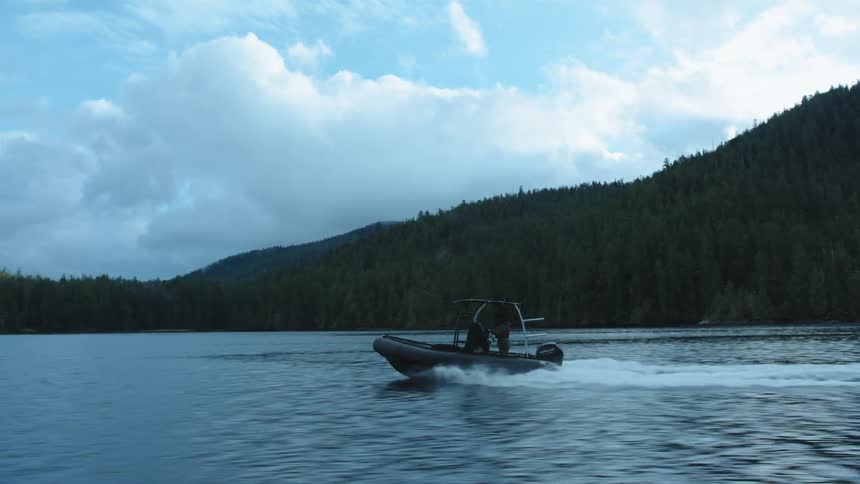 A boat speeding across a mountain lake on a summer day
