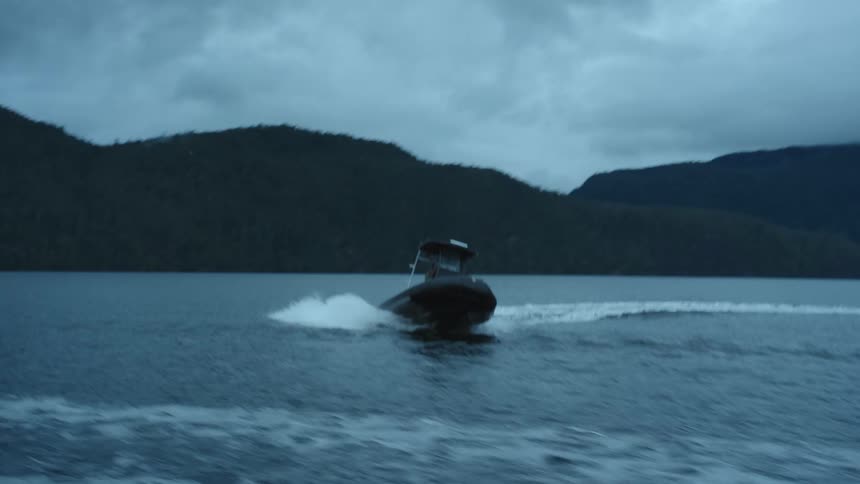 Inflatable boat turning at full speed on a lake in the mountains