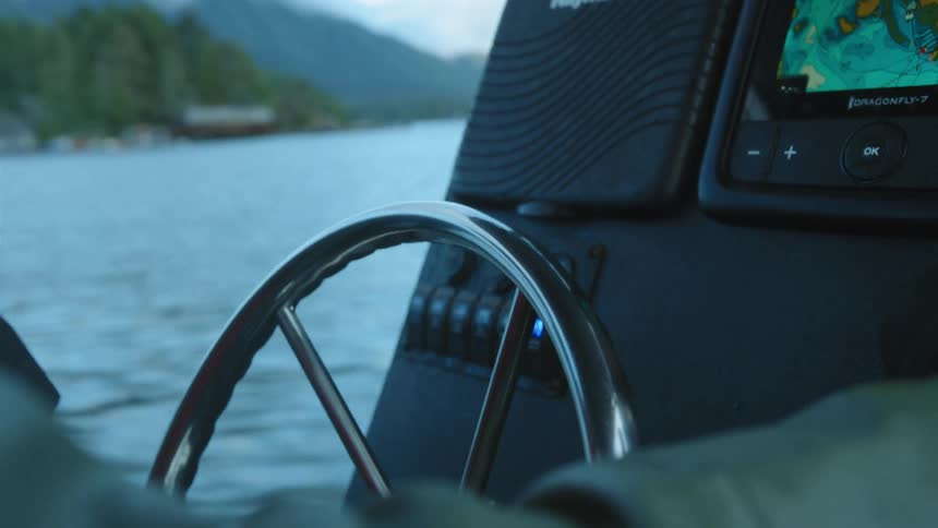 A person turns the wheel on the boat