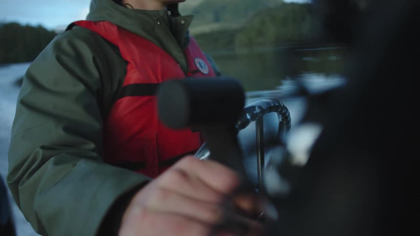 Boat driver wearing a life vest drives the boat in a lake