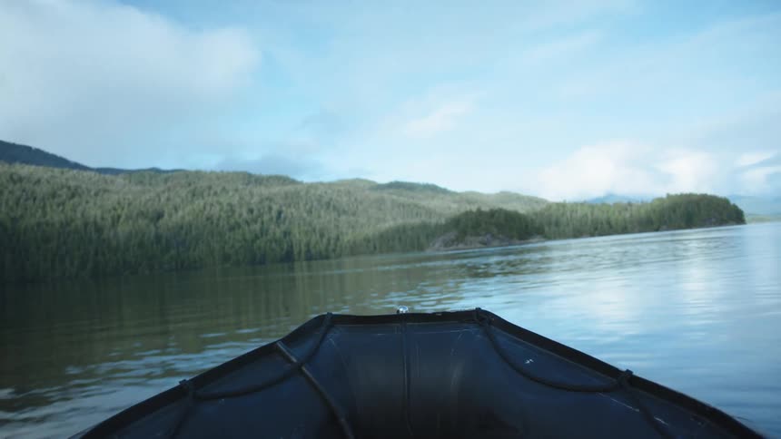 Boat navigates on the surface of a lake near the pine tree forests on the mountain