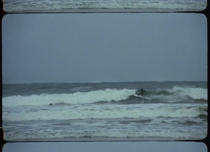 A person surfing on a surfboard on a wave with the sky and clouds in the background