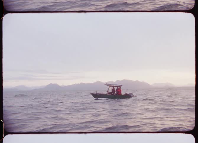 A small boat with people out in the middle of the ocean during the day
