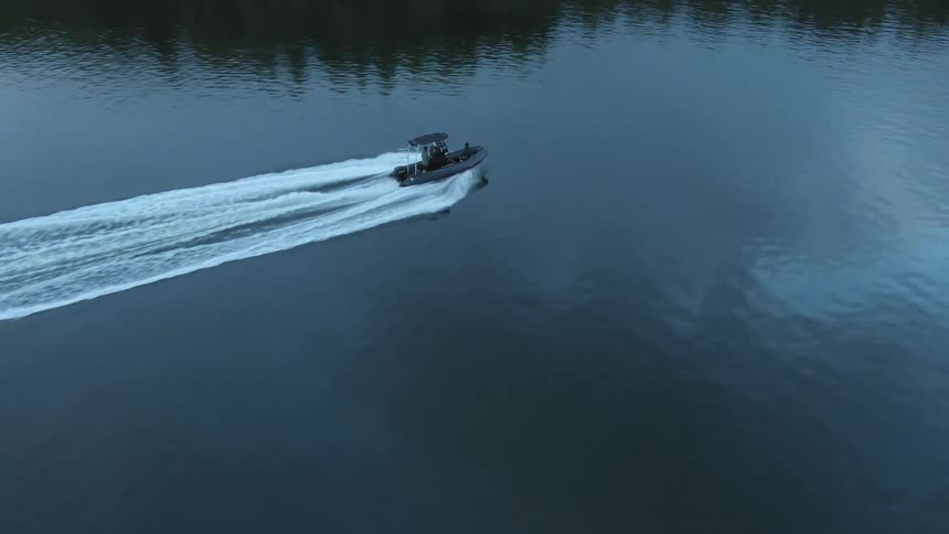 Aerial view of a boat with two people traveling across a lake