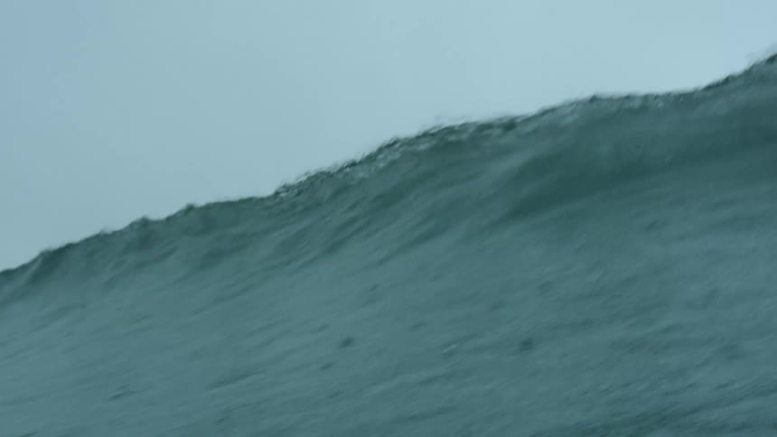 The ocean with a wave of water with the sky and clouds in the background
