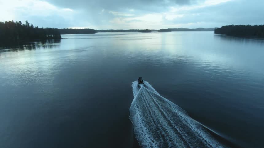 A speedboat sails through water with several small islands covered with trees