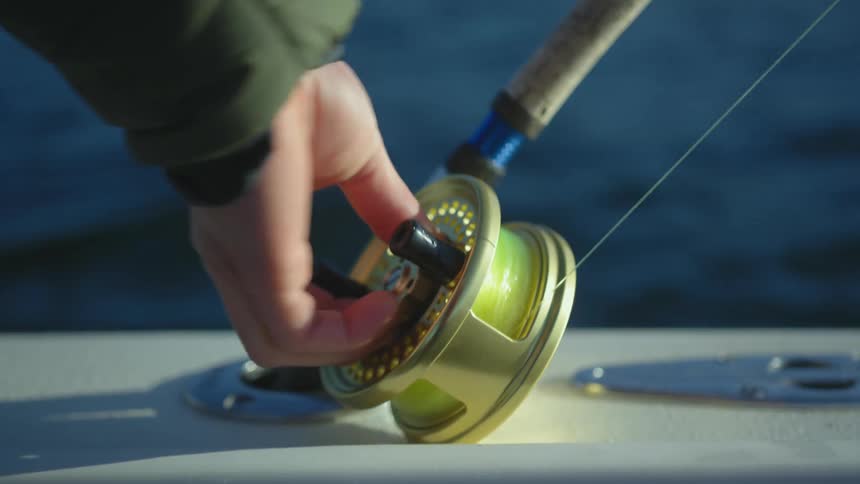 A fishing reel spirals until a hand comes in to stop and position it