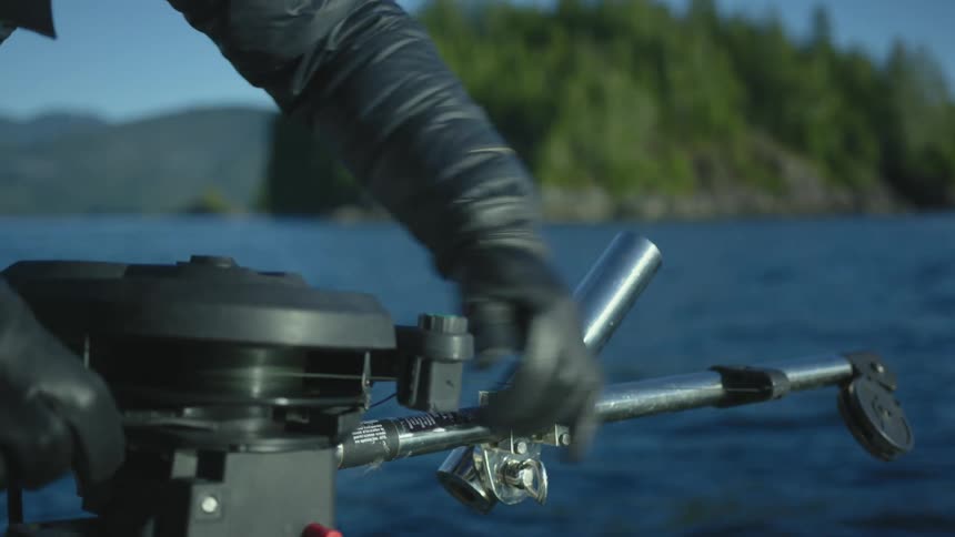 A man is releasing fishing line while wearing gloves