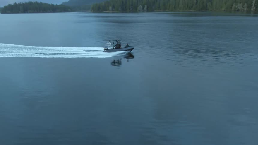 Boat navigates on the surface of a lake near the pine tree forests on the mountain