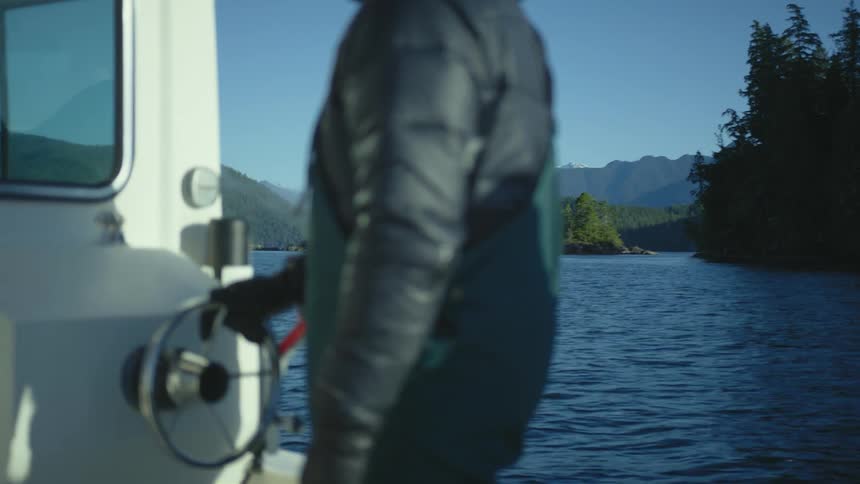 A person on a boat with trees the sky and clouds in the background