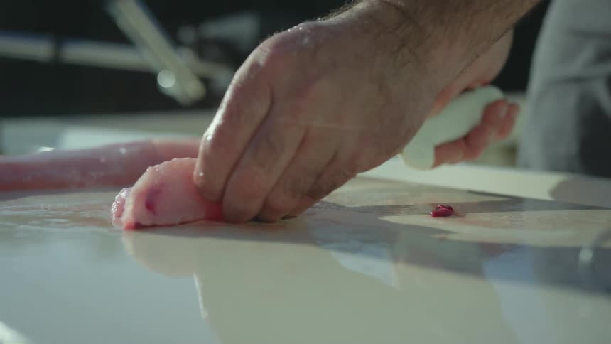 Mans hairy hands cut fish with a knife