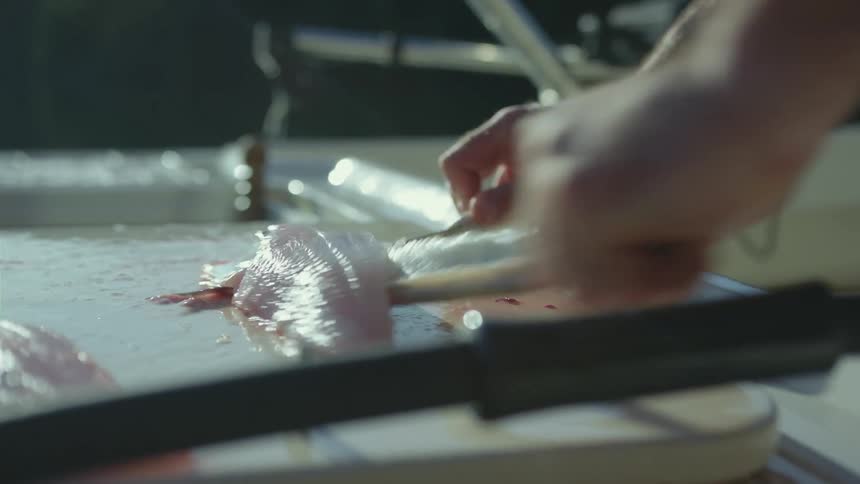 Man cutting fish fillets aboard a fishing boat