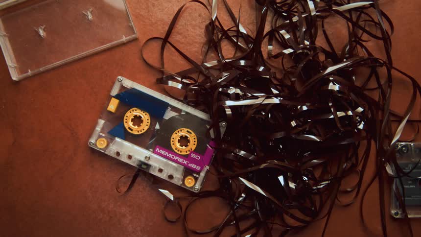 A cassette tape on table with all of its tape reel unraveled