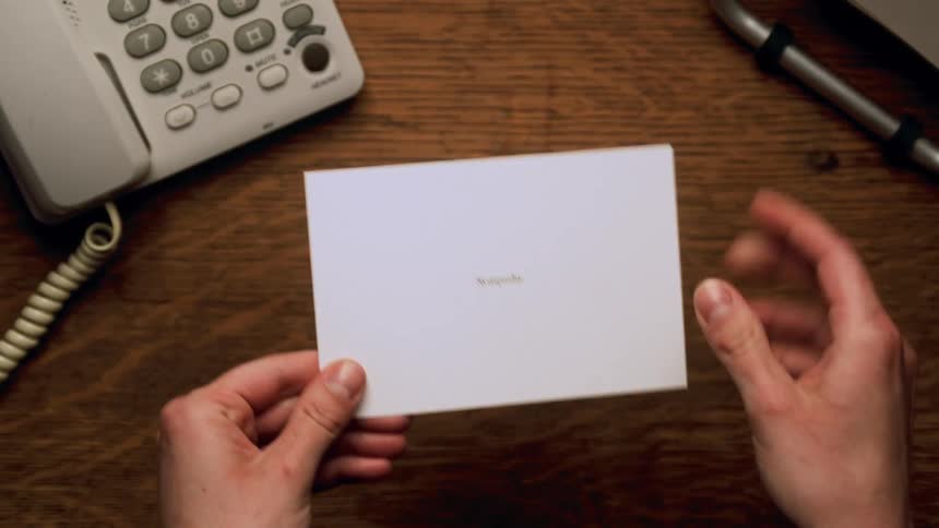 A person opens an envelope over a desk and takes out a letter that reads sucks to be you
