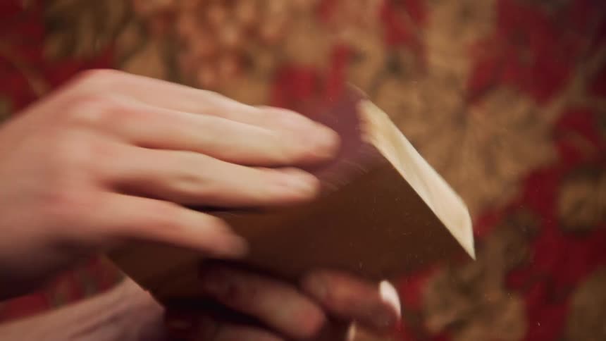 A person sanding a block of wood