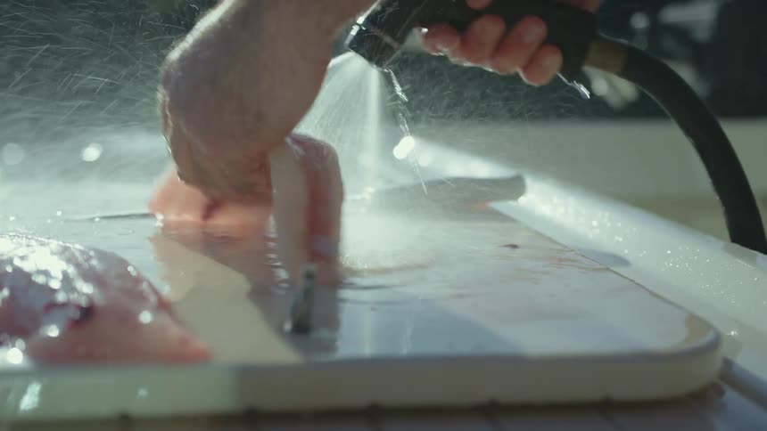 A person is cleaning off two fish slices