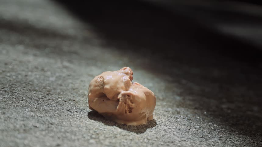 A scoop of chocolate ice cream falls to the floor