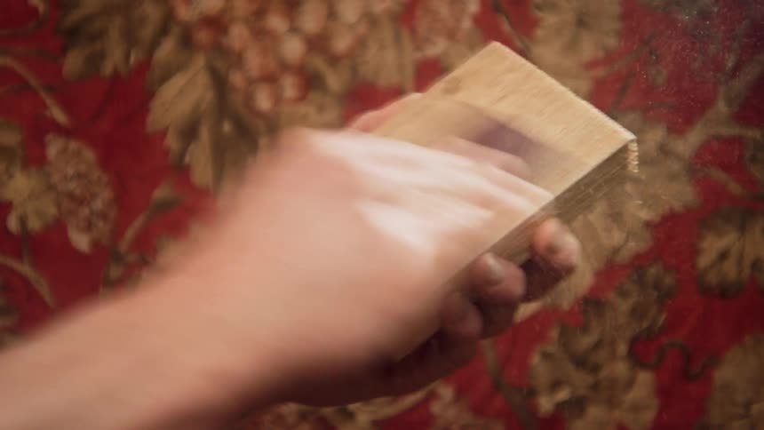 A person quickly sands a block of wood
