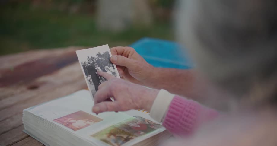 An elderly woman and a man look at old photos