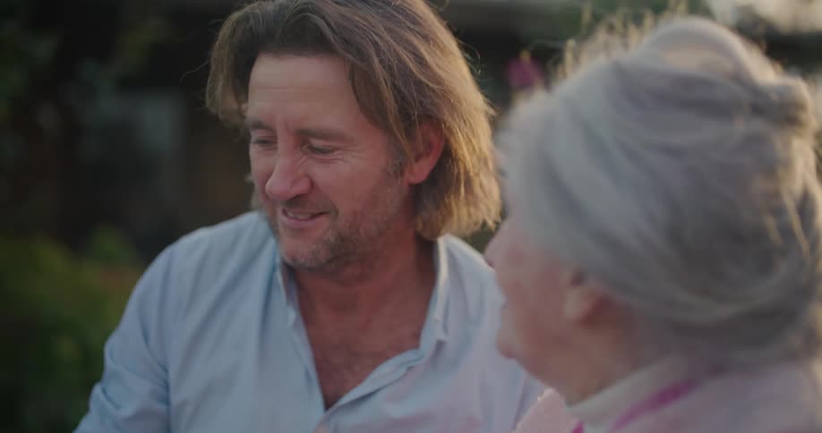 An elderly woman talks with a man outside