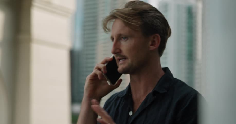 A man talking on a smartphone with a building in the background
