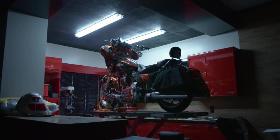 A motorcycle sits on top of a lift inside a large garage
