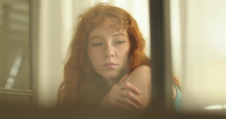 A girl is leaning forward by the window