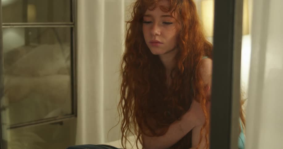 A woman is sitting indoors by a window at night
