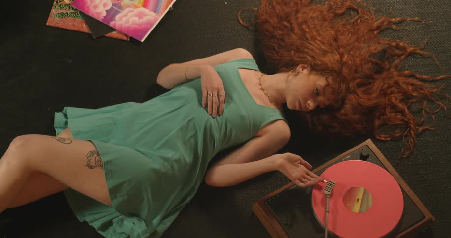 A woman puts the needle on a record to listen