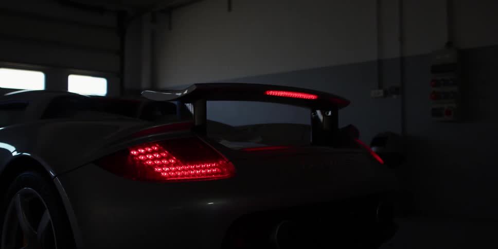 A car in a garage with a trashcan a wall and a door in the background
