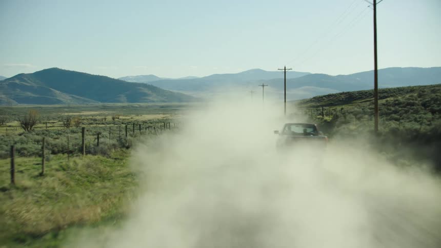 Dust plumes are kicked up high behind a pickup truck in rural Montana showing how swing voters drive far and wide to voting booths on election day