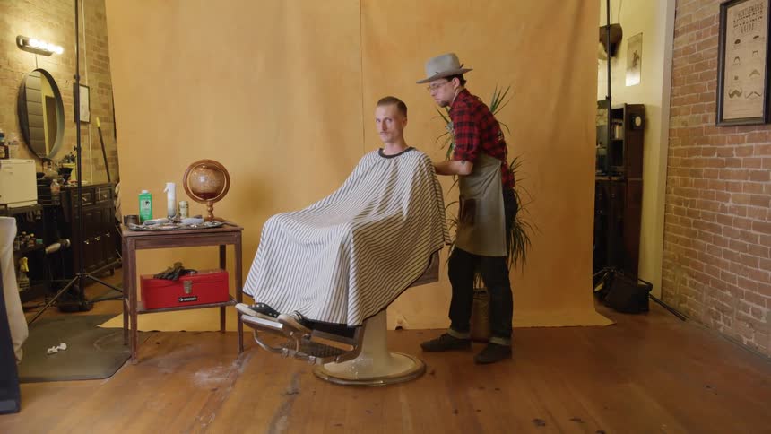 A barber turns a customer around in a chair