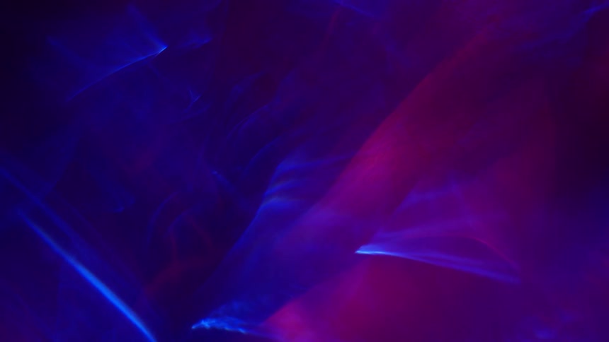 In a dark and surreal setting wisps of purple waves drift past each other