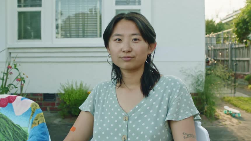 A woman is blinking and looking at the camera while swift breeze is blowing towards her face